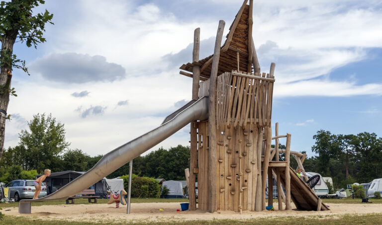 Groot natuurlijk speeltoestel met boulderwand en glijbaan op recreatiepark