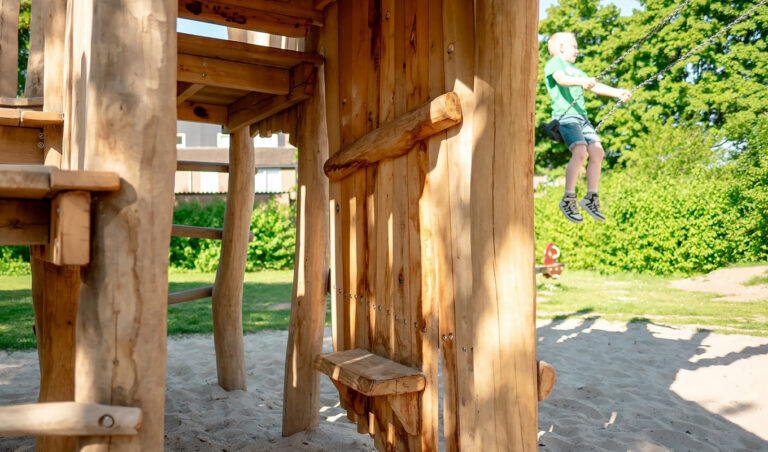 Speeltoestel met speelhuisje en schommel op een speelplek