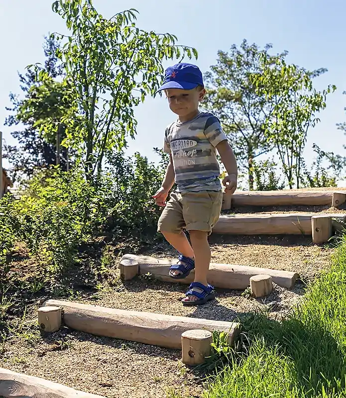 Kind op speelheuvel met trap van houten treden